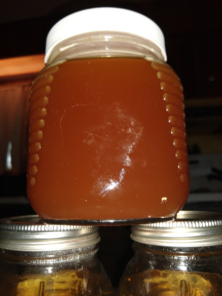 an almost reddish brown mostly opaque liquid in a short glass jar.